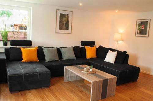 ein Wohnzimmer mit einem schwarzen Sofa und einem Tisch in der Unterkunft Ferienhaus Pape Gleidorf in Schmallenberg