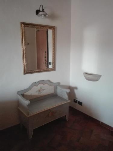 a mirror on a wall with a bench in a room at La Casina in Asciano