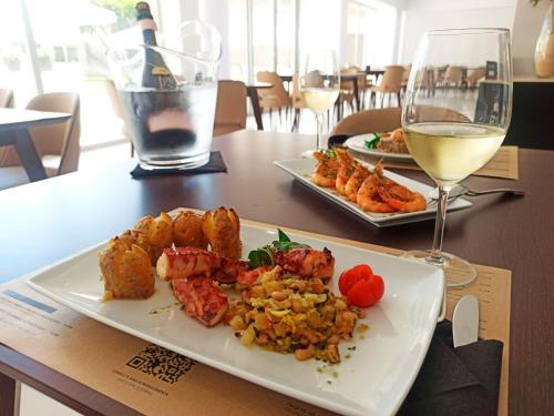 a table with two plates of food and a glass of wine at QH Praia de Quiaios in Praia de Quiaios
