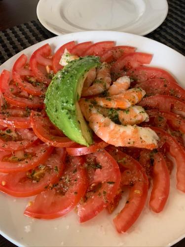 a plate of shrimp and tomatoes with a pickle at ATICO LA ILUSION CON PARkING in Sanlúcar de Barrameda