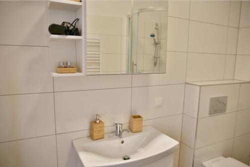 een witte badkamer met een wastafel en een spiegel bij Zwischen Schönbrunn und dem City Center. Apt. 33 in Wenen