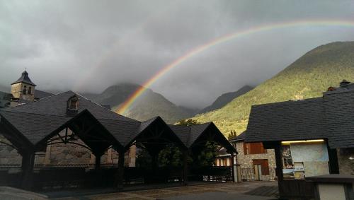 a rainbow over a building with mountains in the background at Apartamento céntrico, destino Sallent de Gallego in Sallent de Gállego