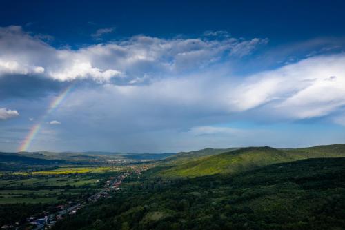 a rainbow in the sky over a valley at Căsuța de sub deal - Ciubăr și piscină in Măgura