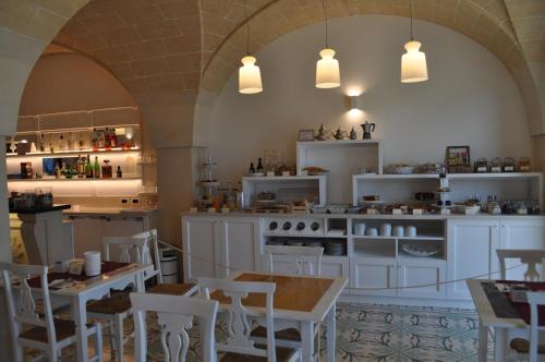 a kitchen with white cabinets and white tables and chairs at Villa Rosa Antico Dimora Storica in Otranto