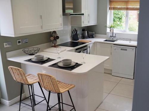 a kitchen with a white island with two stools at The Pavilion - Stunning, 4 Bedroom House with Free Parking in Wakefield