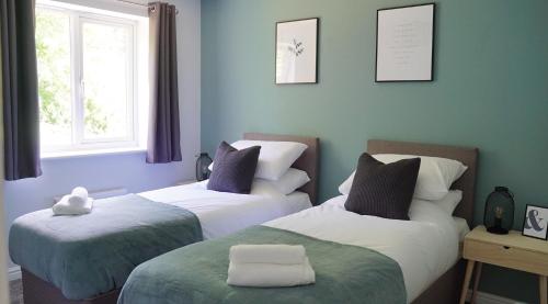 Duas camas num quarto com paredes azuis em The Pavilion - Stunning, 4 Bedroom House with Free Parking em Wakefield