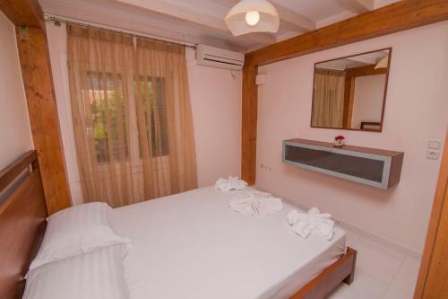 a bedroom with a white bed and a mirror at Orfeas Studios in Vasiliki