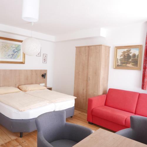 a bedroom with a bed and a red couch at Appartement Katharina 2 Personen Hallein bei Salzburg in Hallein