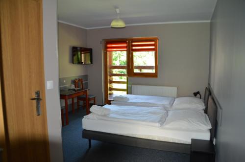 a bedroom with a white bed and a window at Hotel Tenis in Chrząstowice