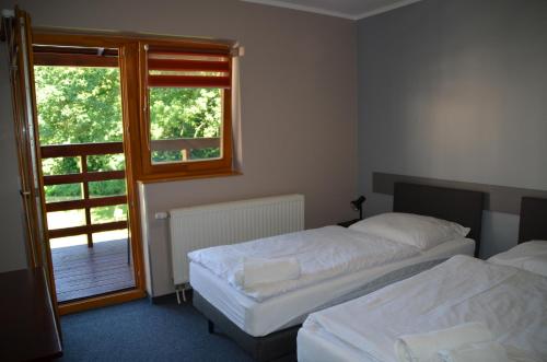 two beds in a room with a window at Hotel Tenis in Chrząstowice