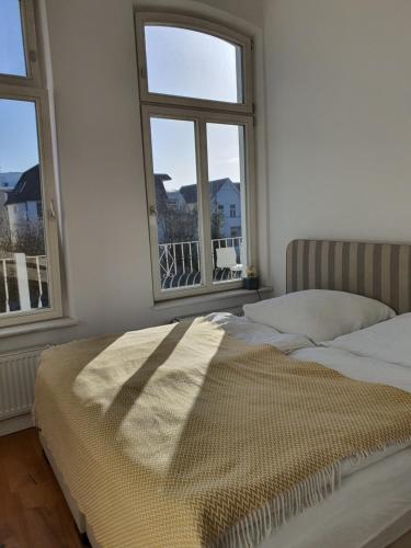 - un lit dans une chambre avec 2 fenêtres dans l'établissement Großzügige,98m2 grosse Wohnung in stadtnaher Traumlage, nur 200m zum Stadtpark, à Oldenbourg