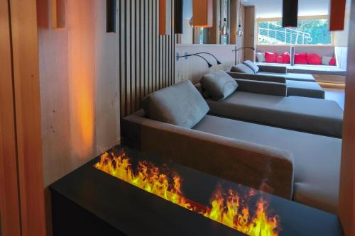 a room with three couches and a fire in a fireplace at Hotel Garni Herz in Tirolo