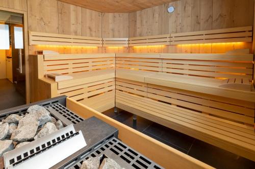 a sauna with wooden walls and benches and rocks at Hotel Garni Herz in Tirolo