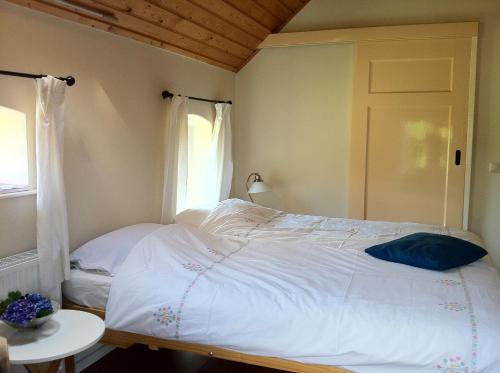 a bedroom with a white bed with a window at De Bolderie in Markelo