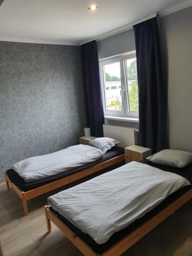 two beds in a room with a window at Noclegi Róża Wiatrów in Górowo Iławeckie