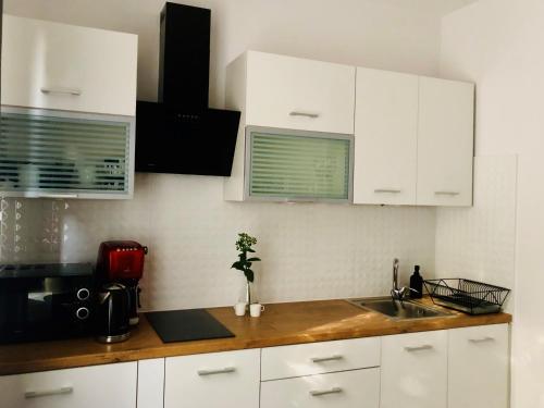 una cocina con armarios blancos y fregadero en Nico Apartments, en Cracovia