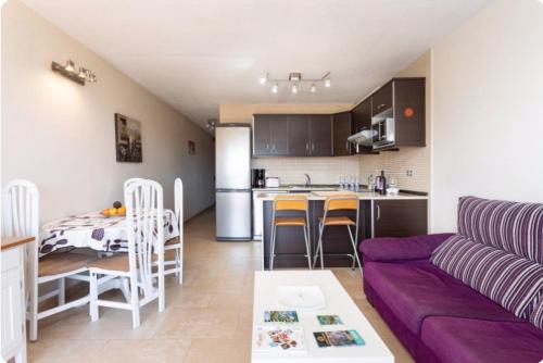 ein Wohnzimmer und eine Küche mit einem lila Sofa in der Unterkunft Listen the SILENCE - 355 in Arona