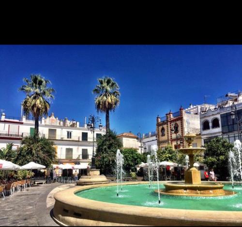a fountain in the middle of a city with palm trees at ATICO LA ILUSION CON PARkING in Sanlúcar de Barrameda