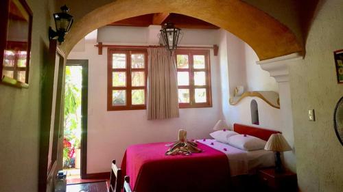 a bedroom with a red bed and a window at Hotel Las Golondrinas in Oaxaca City