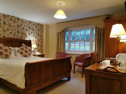 una camera da letto con un letto, un tavolo e delle sedie di Rose in Vale Country House Hotel a St. Agnes 