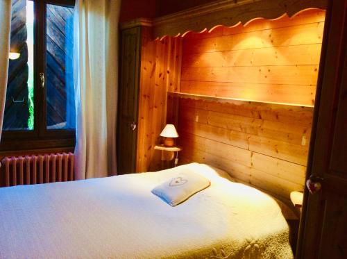 a bedroom with a white bed with a wooden wall at Au Refuge de Blanche in Verchères