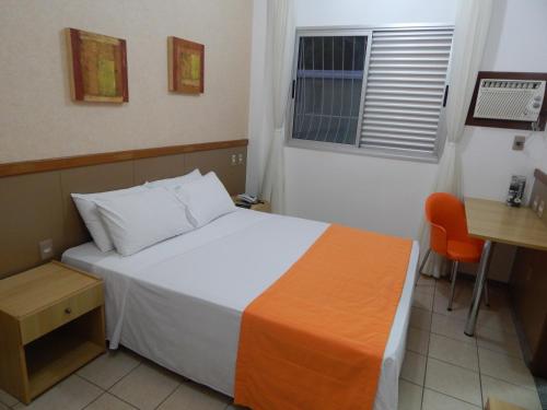 a hotel room with a bed and a desk at Frimas Hotel in Belo Horizonte
