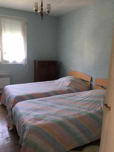 - 2 lits dans une chambre avec des murs bleus et une fenêtre dans l'établissement Chez Jacques et Annick, à Grandcamp-Maisy