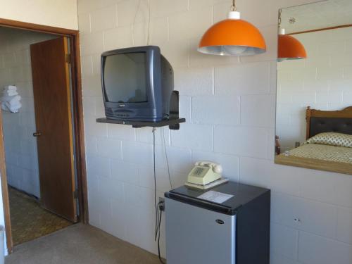 a tv on a wall with a phone on a table at Alamo Inn in Alamo