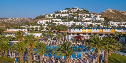a resort with palm trees in front of a mountain at Lagas Aegean Village in Kardamaina