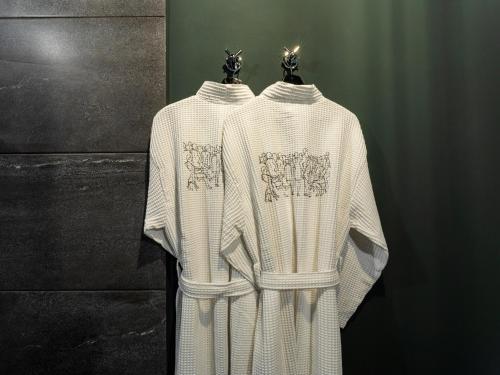 two white sweaters are hanging on a wall at Esquisse Design Hotel in Tʼelavi