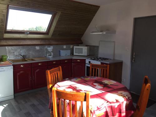 une cuisine avec une table et des chaises et une fenêtre dans l'établissement Chez Jacques et Annick, à Grandcamp-Maisy