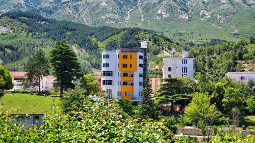 a building on a hill with mountains in the background at Alvero Hotel in Përmet