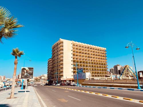 een hoog gebouw in een stadsstraat met een palmboom bij Semiramis Hotel Royal Palace in Marsa Matruh