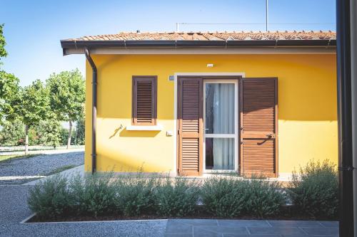 a yellow house with wooden shutters and a door at Hotel Residence Vallecorsa in Vada