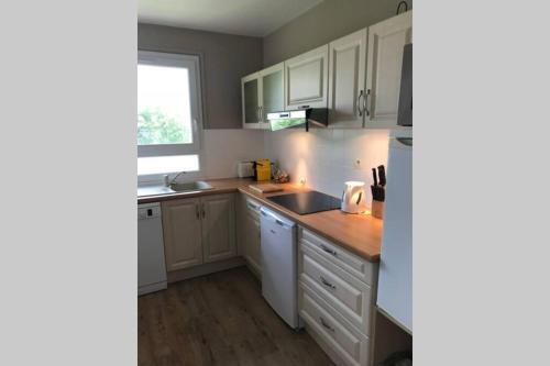 une cuisine avec des armoires blanches, un évier et une fenêtre dans l'établissement Appartement avec vue imprenable sur la mer, à Trouville-sur-Mer