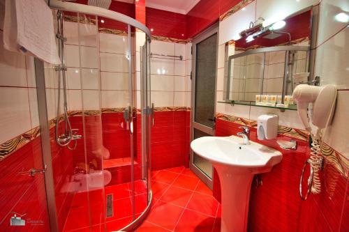 La salle de bains rouge est pourvue d'une douche et d'un lavabo. dans l'établissement Alvero Hotel, à Përmet