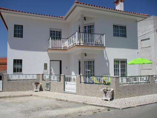 a large white house with a green umbrella at HOMELIDAYS CLARA NAZARE in Nazaré