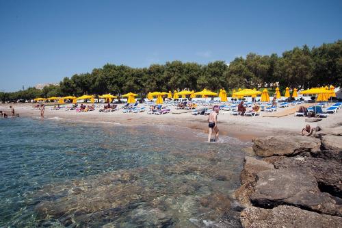 a group of people on a beach with yellow umbrellas at Lagas Aegean Village in Kardamaina
