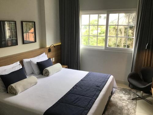 um quarto com uma cama grande e uma janela em Flat Itaipava - Granja Brasil em Itaipava