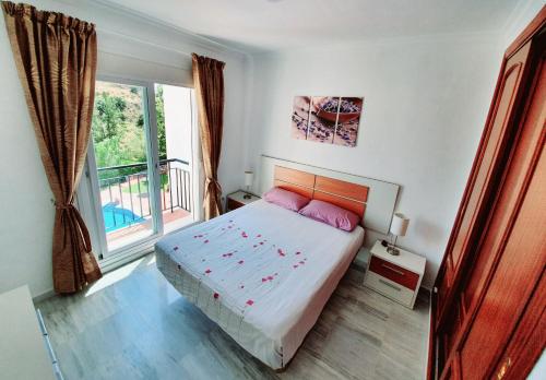 a bedroom with a bed with pink pillows and a window at Vista Alhaurin Golf in Alhaurín el Grande