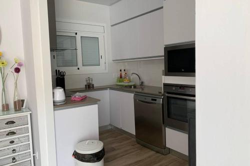 a kitchen with white cabinets and a stove top oven at Lovely house near the beach in Calafell