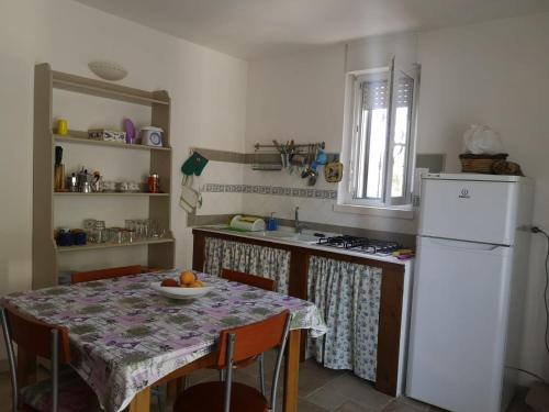 een keuken met een tafel en een witte koelkast bij Trullo Maria in Carovigno