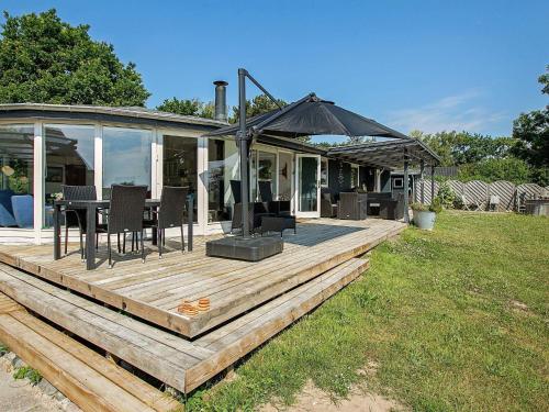 a wooden deck with a table and an umbrella at 8 person holiday home in Tranek r in Fæbæk