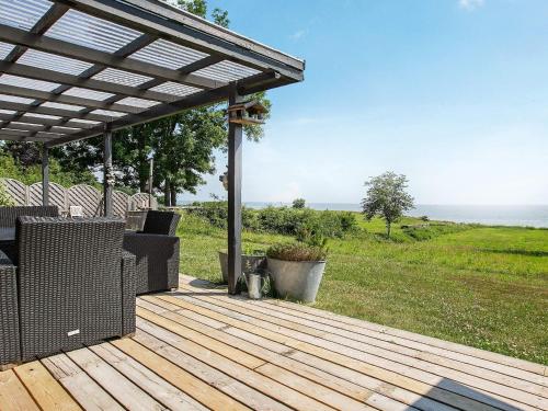 a wooden deck with a pergola overlooking the ocean at 8 person holiday home in Tranek r in Fæbæk