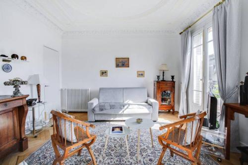 ein Wohnzimmer mit einem Sofa, einem Tisch und Stühlen in der Unterkunft Trocadéro in Paris