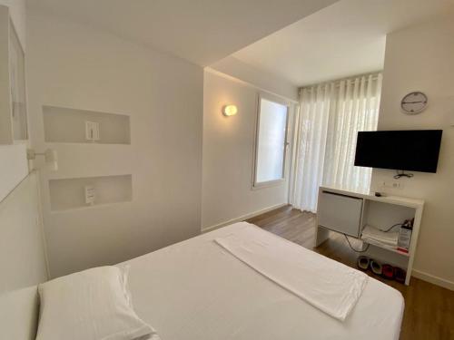 a white bedroom with a bed and a flat screen tv at Aleksi rooms in Shëngjin