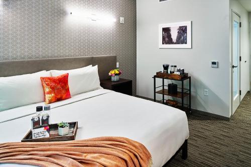 a bedroom with a large white bed with red pillows at Hotel Mariposa in Los Angeles