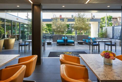 a restaurant with orange chairs and tables and windows at Hotel Mariposa in Los Angeles