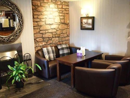 a waiting room with a table and leather chairs at Inchture Hotel in Dundee