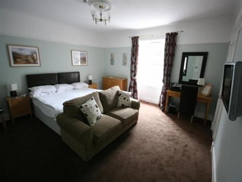 a bedroom with a bed and a couch and a television at Inchture Hotel in Dundee